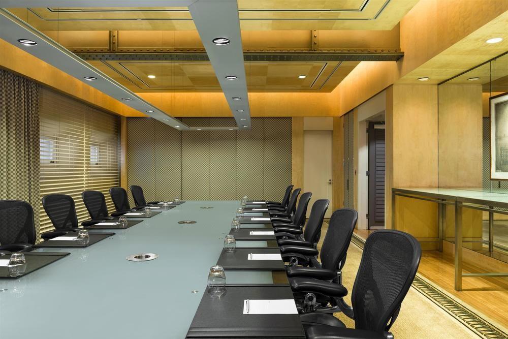 더 풀러턴 호텔 시드니 외부 사진 The photo shows a modern conference room with a long, rectangular table at the center. There are several ergonomic office chairs lined up on either side of the table. The tabletop appears to be a light-colored glass or a similar material, and it has 