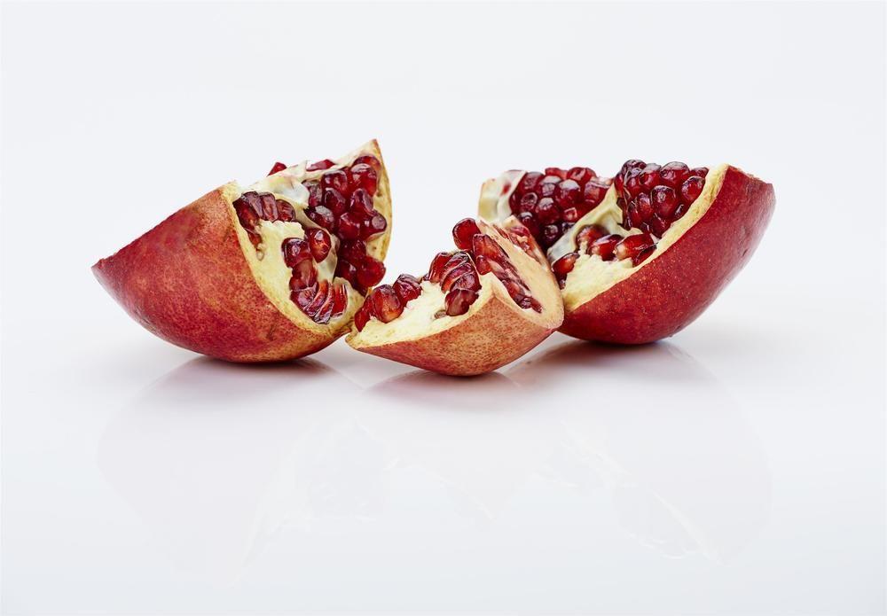 더 풀러턴 호텔 시드니 외부 사진 The photo shows pomegranate fruit that has been cut into sections. The outer skin is reddish-brown, and the inside reveals juicy, bright red seeds, known as arils. The pieces are arranged on a white surface, highlighting the contrast between the vibr